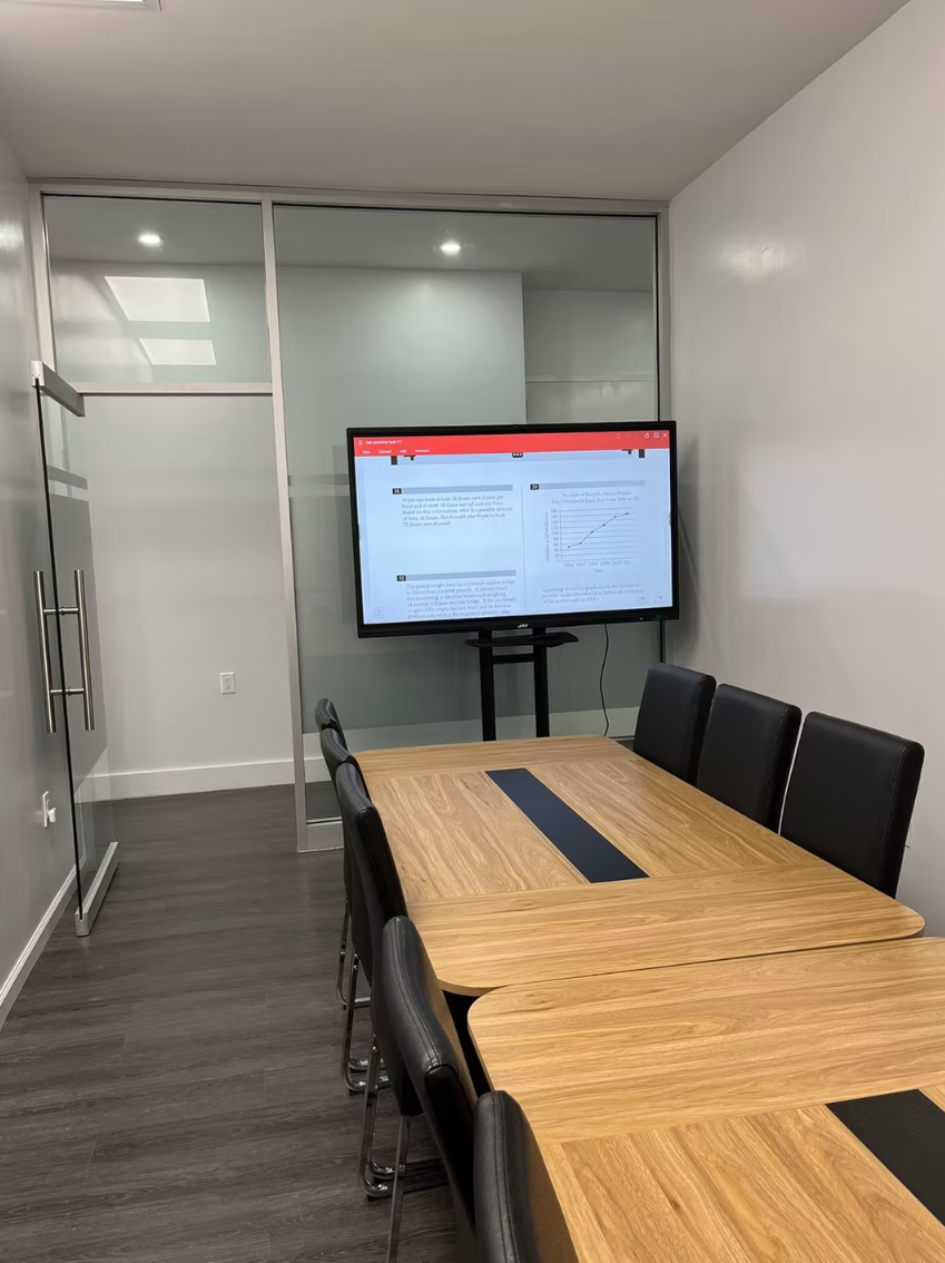 ToIvy mock test room with wood conference table and SAT practice displayed on screen